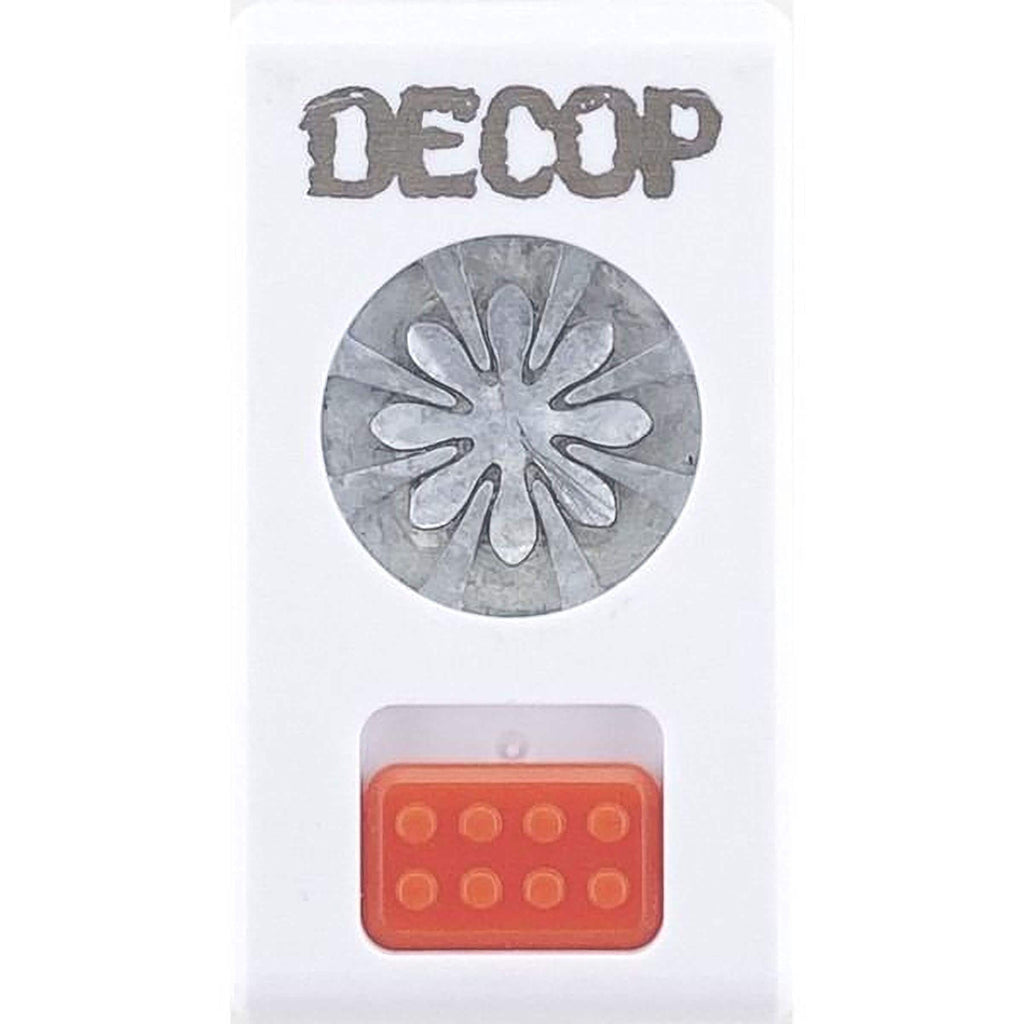 a white object with a silver flower-like design on it, and there is an orange object below it.