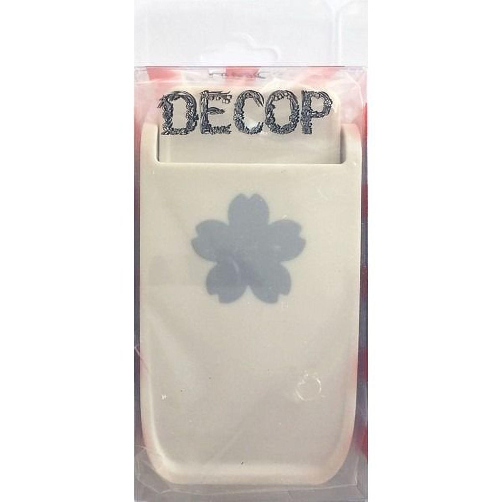 a white plastic object with a black flower design on it, which appears to be a product packaging.