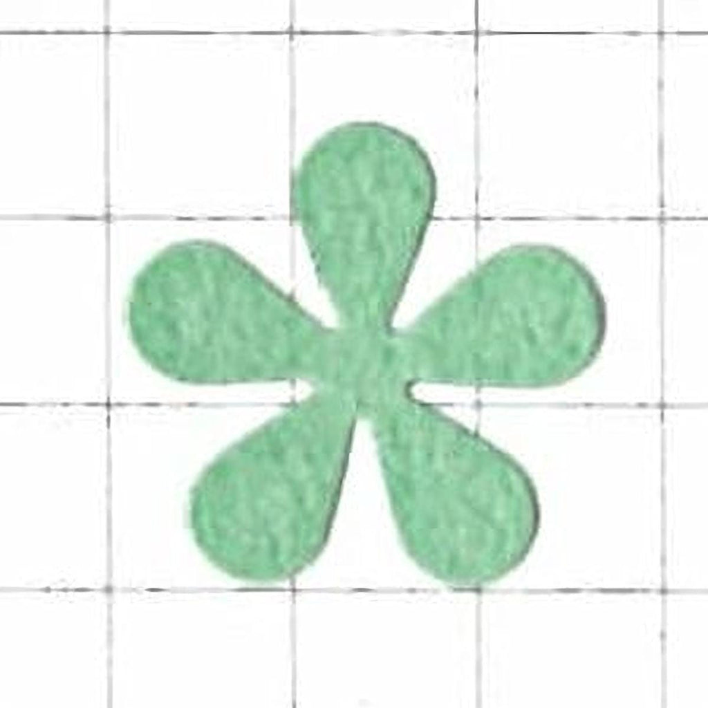 A green felt flower-shaped object is centered against a white grid background.