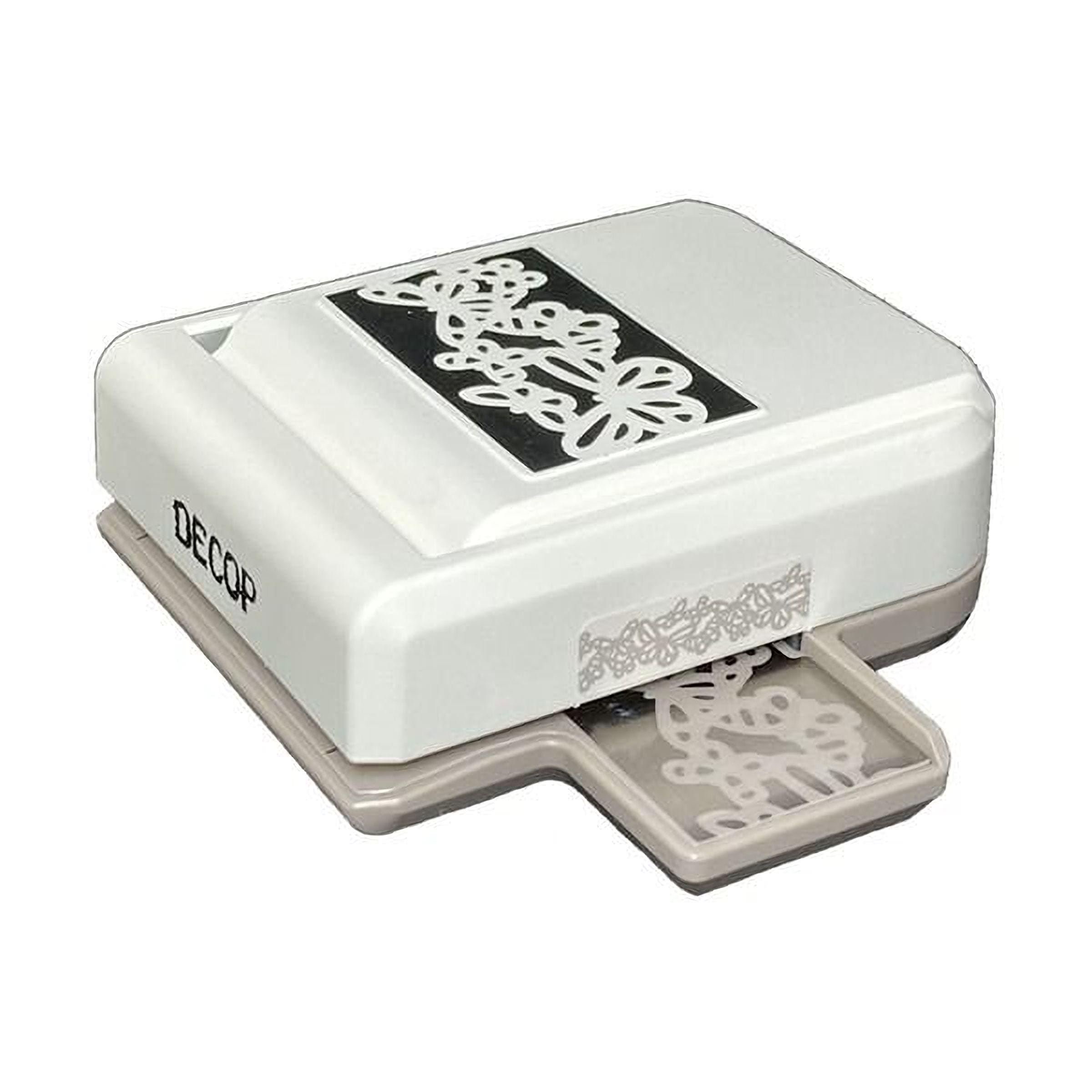 A white and black decorative punch or cutter with a floral pattern on the front.