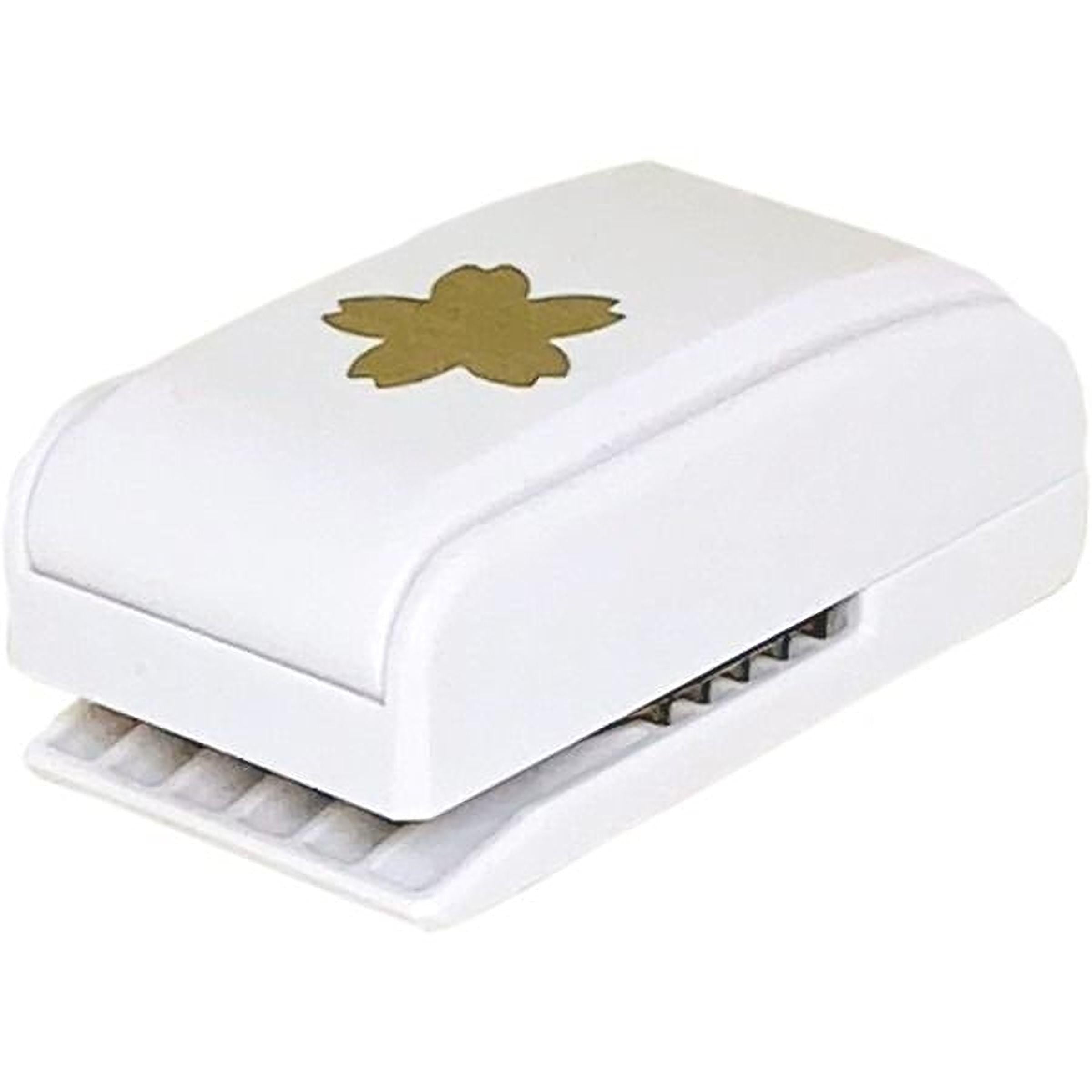 A white, rectangular hole puncher with a gold flower design on the top surface.