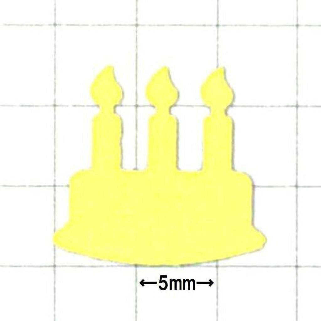 A yellow cake-shaped object with three candles on top, placed against a grid background.