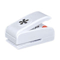 A white plastic hole puncher with a black flower design on the top.