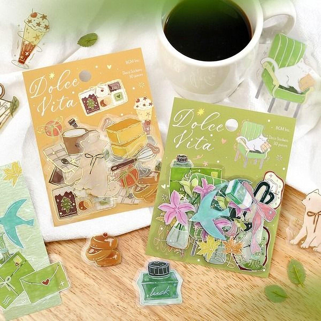 two packages of decorative stickers, a cup of coffee, and various other items such as a bird, a cat, and a chair, all arranged on a wooden surface.