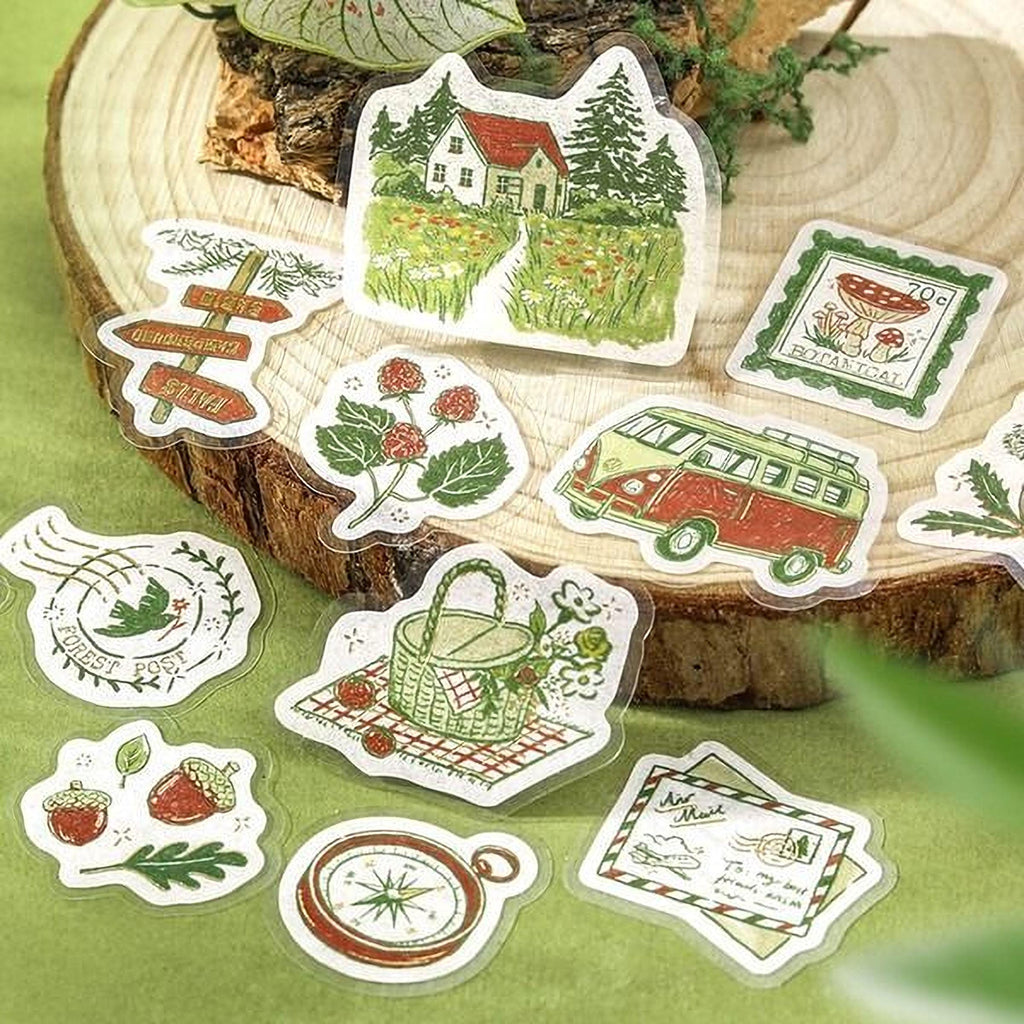 a collection of various stickers, including a house, mushrooms, a van, and other nature-themed illustrations, all set against a wooden background.