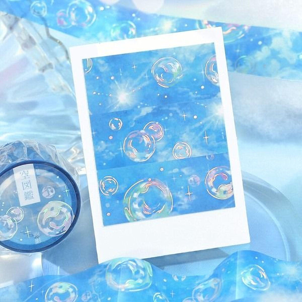 a white card with a pattern of colorful bubbles floating in the air, along with a blue and white striped object and a blue and white striped object in the background.