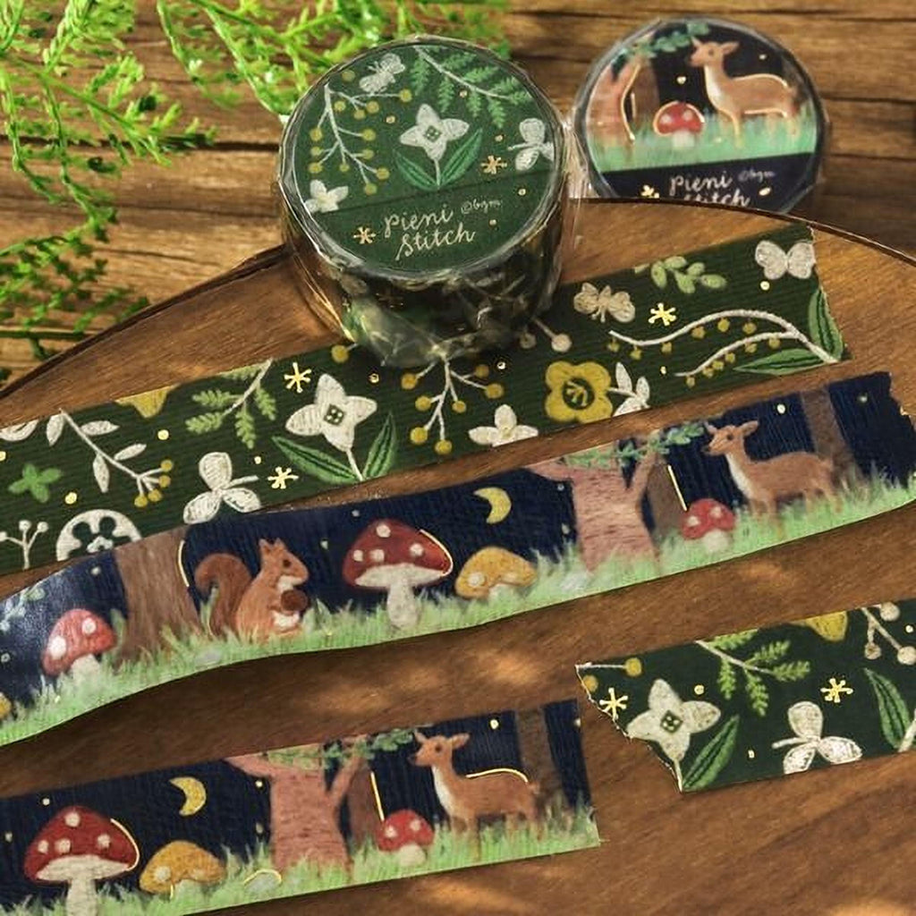 a collection of decorative items, including a circular object with a floral design, a roll of tape with a forest-themed design, and several pieces of tape with various animal and nature-inspired designs.