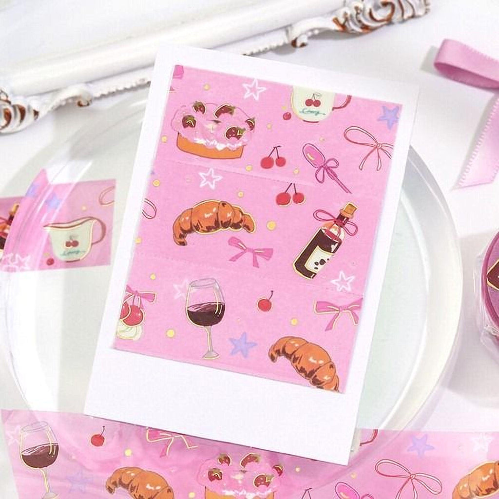 a pink card with various food and drink items such as a cake, wine glass, bottle, and cherries, along with other decorative elements like stars and bows.