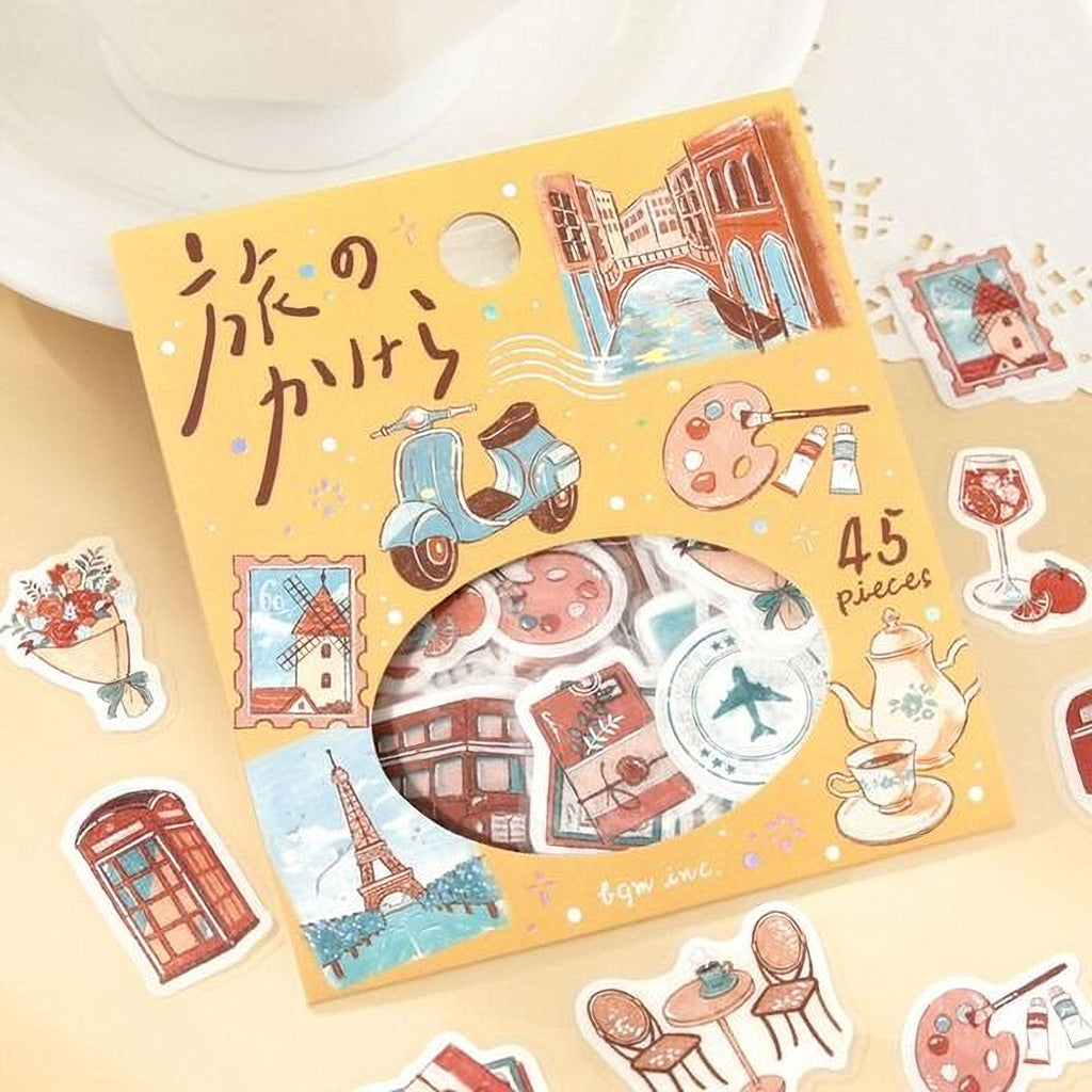 a yellow box with various stickers and illustrations of different objects and scenes, including a moped, a building, a teapot, and other decorative elements.