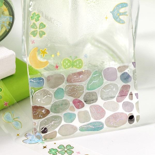 a clear glass jar with a colorful, patterned design on its surface, including various shapes, symbols, and a bird.