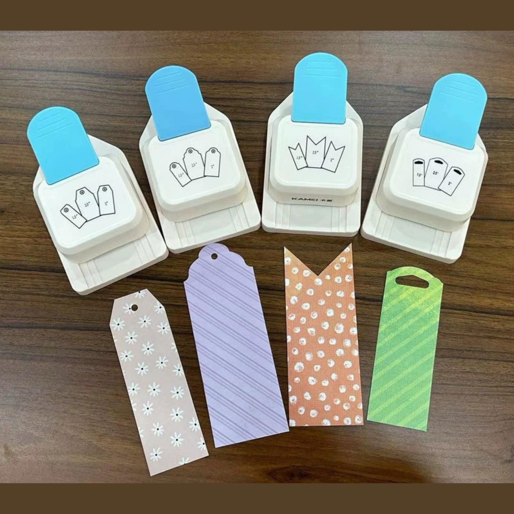 four push-type hole punchers with blue handles, arranged on a wooden surface alongside various colorful paper tags.