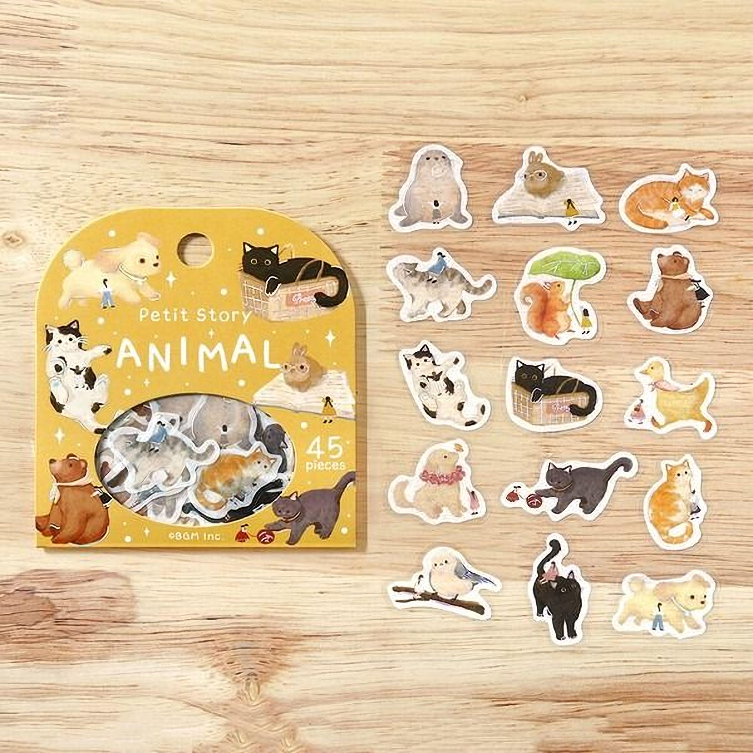 a yellow box of stickers with various animal illustrations, including cats, dogs, and birds, alongside a collection of small animal stickers on a wooden surface.