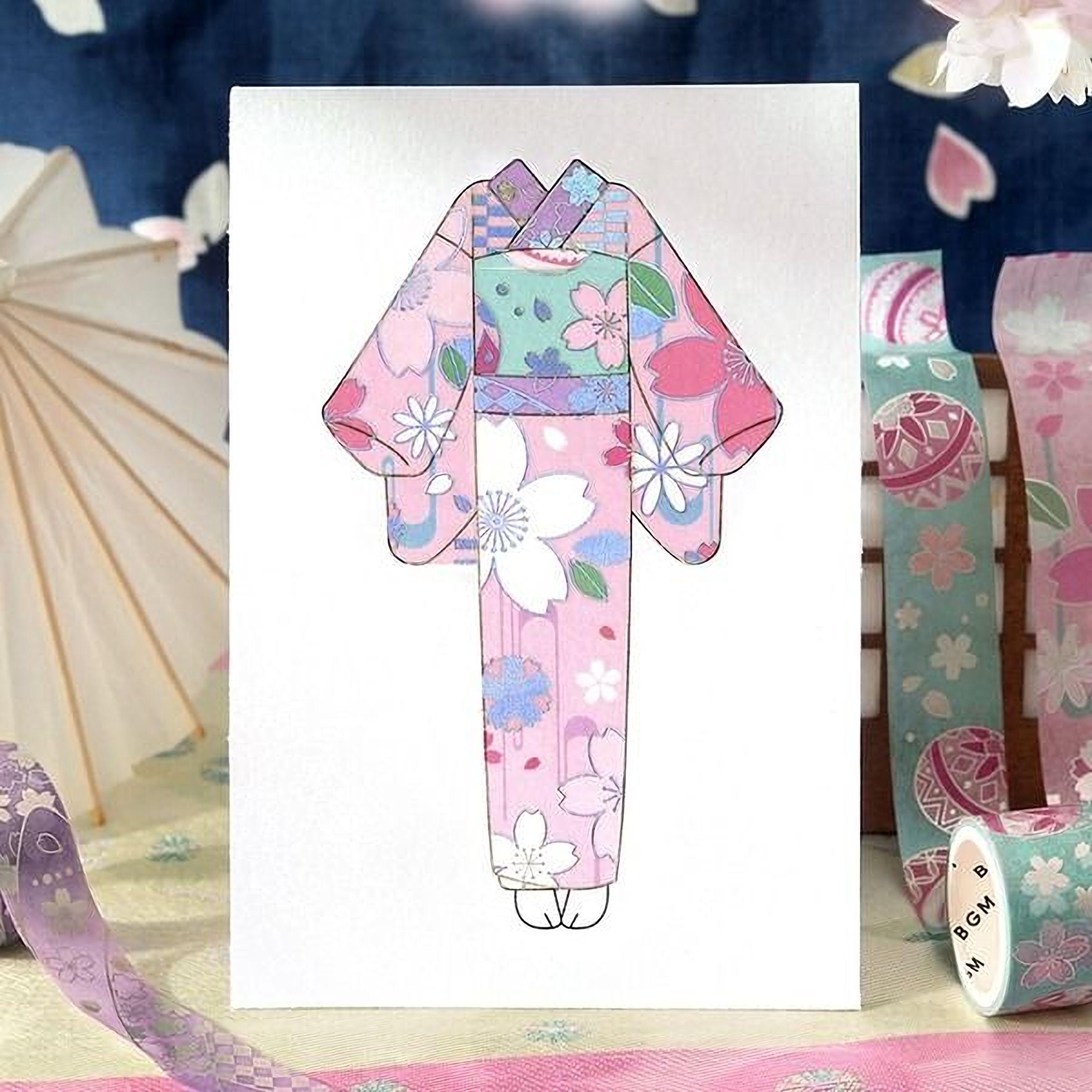 A colorful kimono with a floral pattern is displayed on a white background, surrounded by various decorative items such as a white umbrella, a pink and white floral pattern, and a roll of tape.
