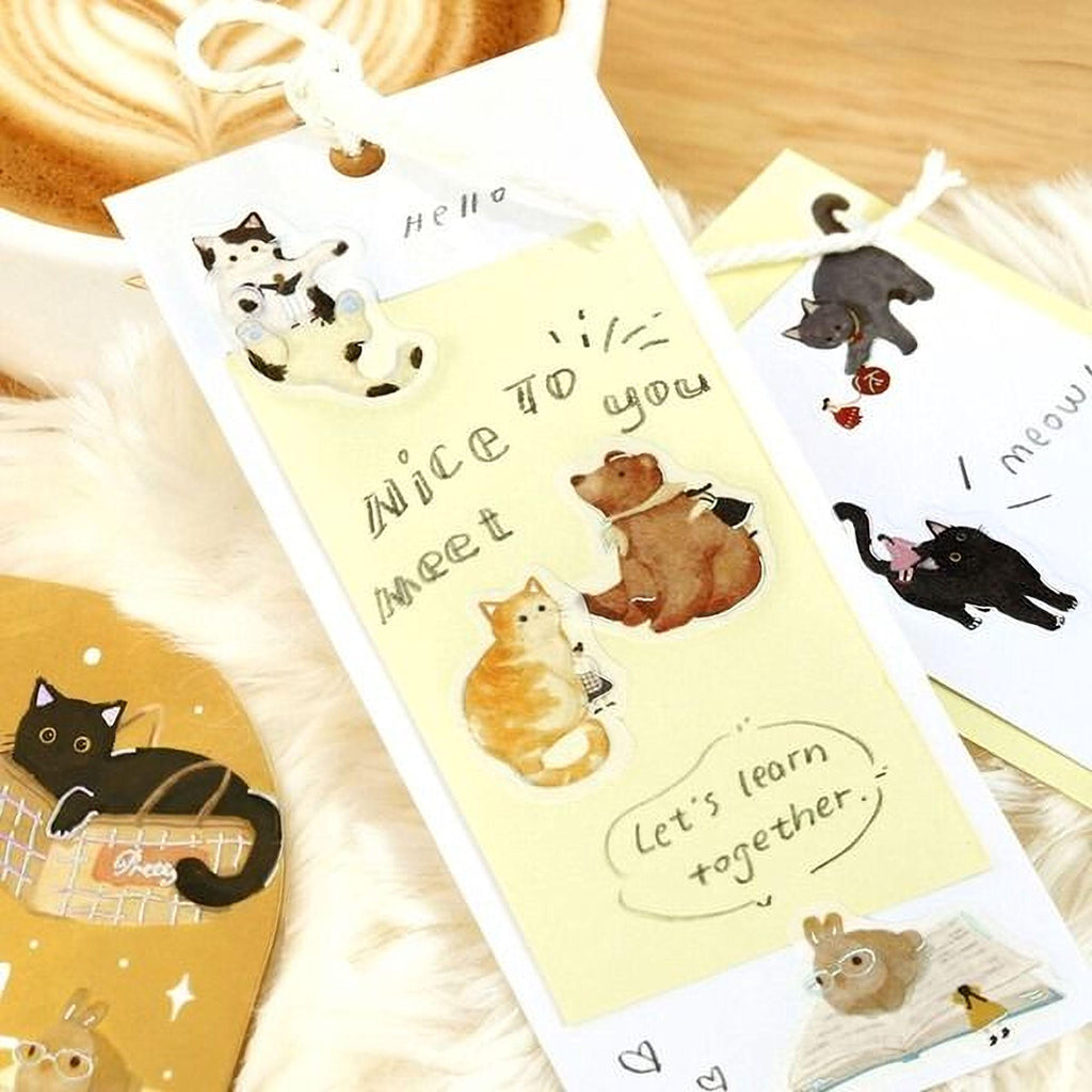 a collection of stickers and cards with various cat illustrations, including a yellow card with a message that says " Nice to meet you" and a black cat sticker.