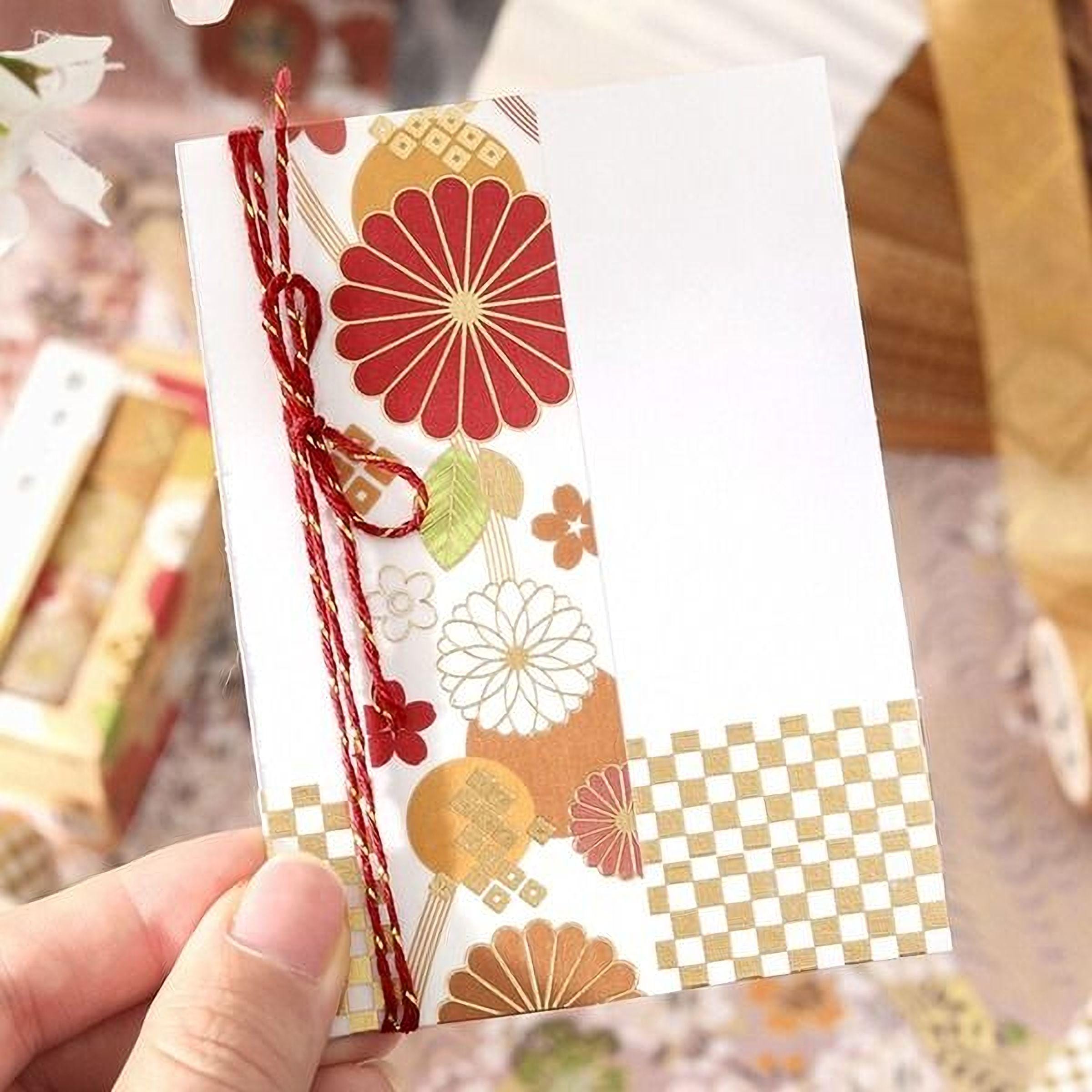 A hand holding a card with a floral pattern and a checkered border.