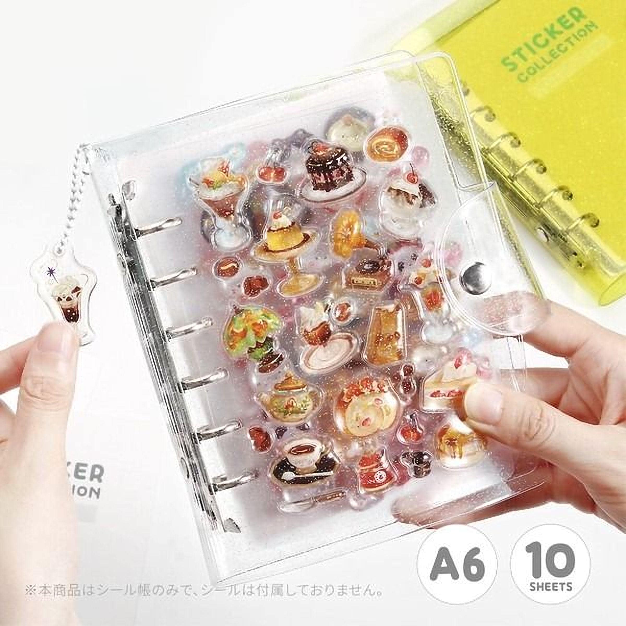 A transparent notebook with various food-themed stickers attached to it, held in someone's hands.