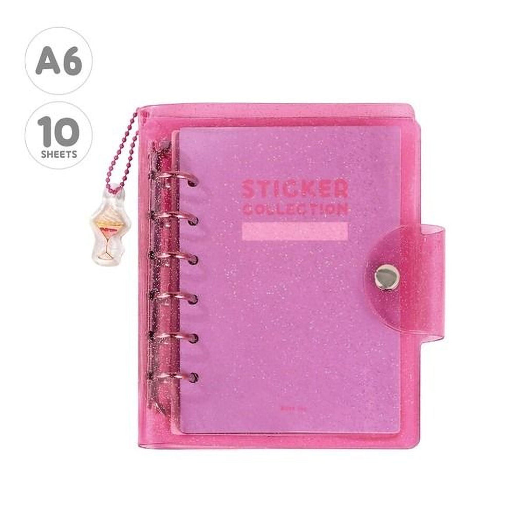 A pink glittery notebook with a spiral binding and a charm attached to it.