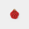 A red and gold pendant with a braided design is shown against a white background.