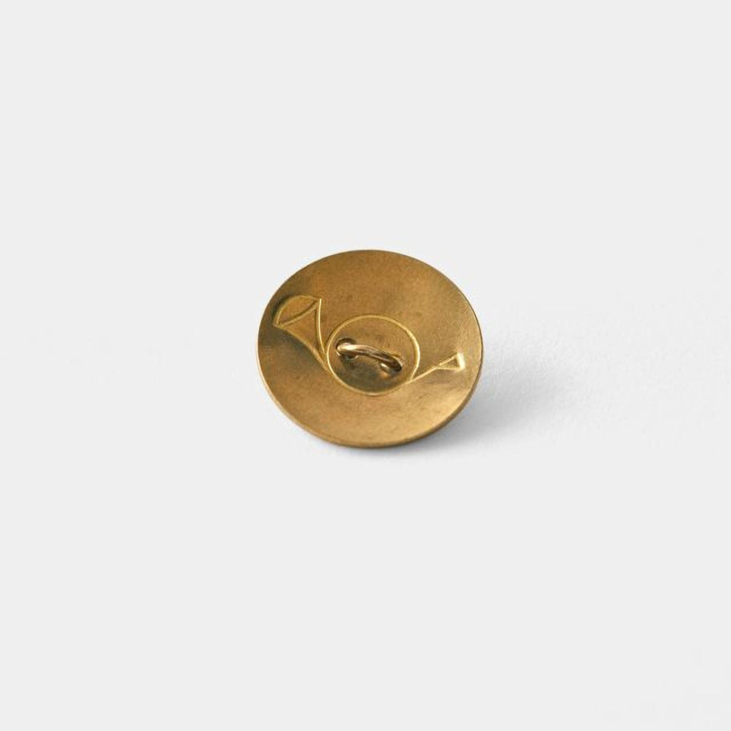 A single, round, gold-colored button with a unique design is shown against a plain white background.