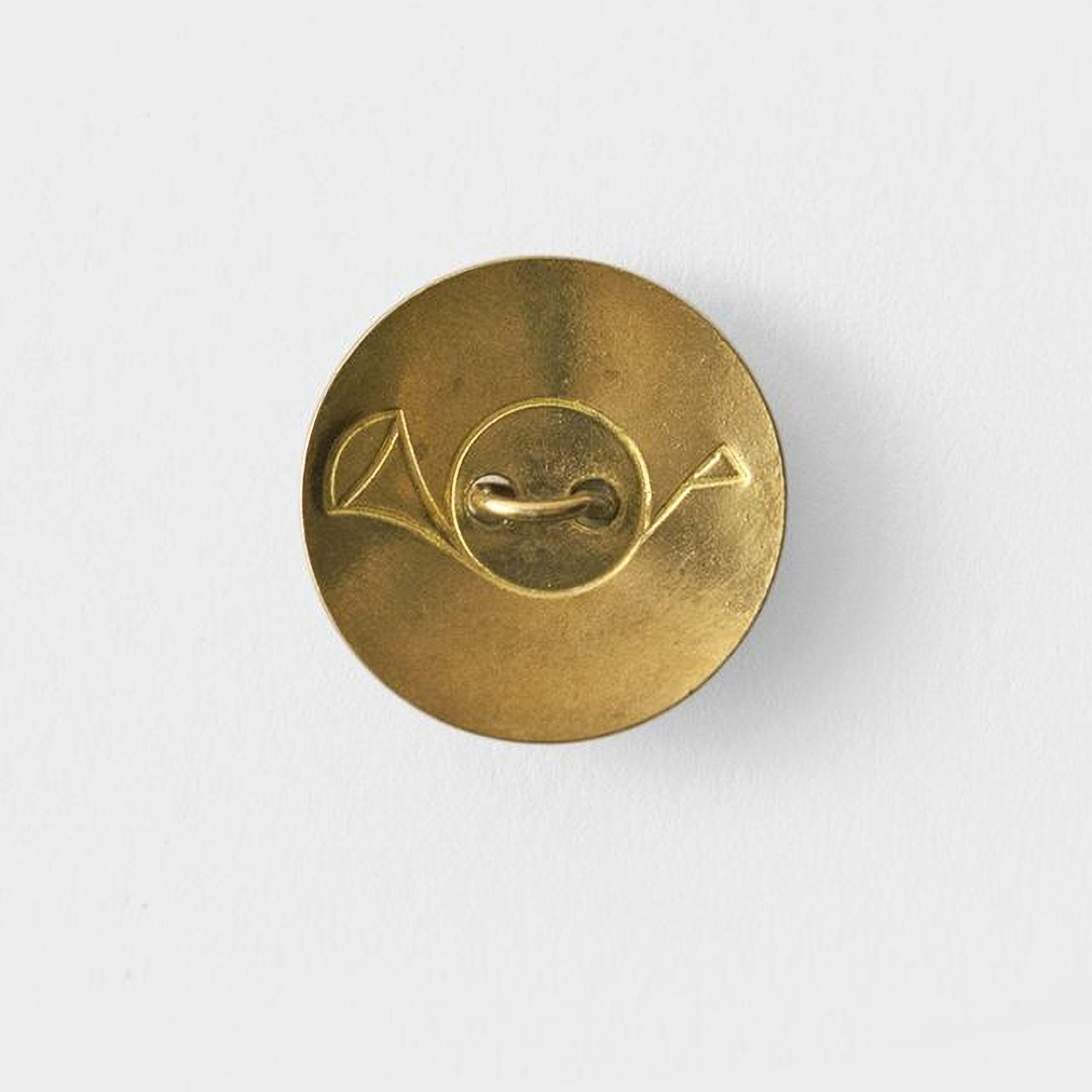 A round, gold-colored button with an embossed design on it.