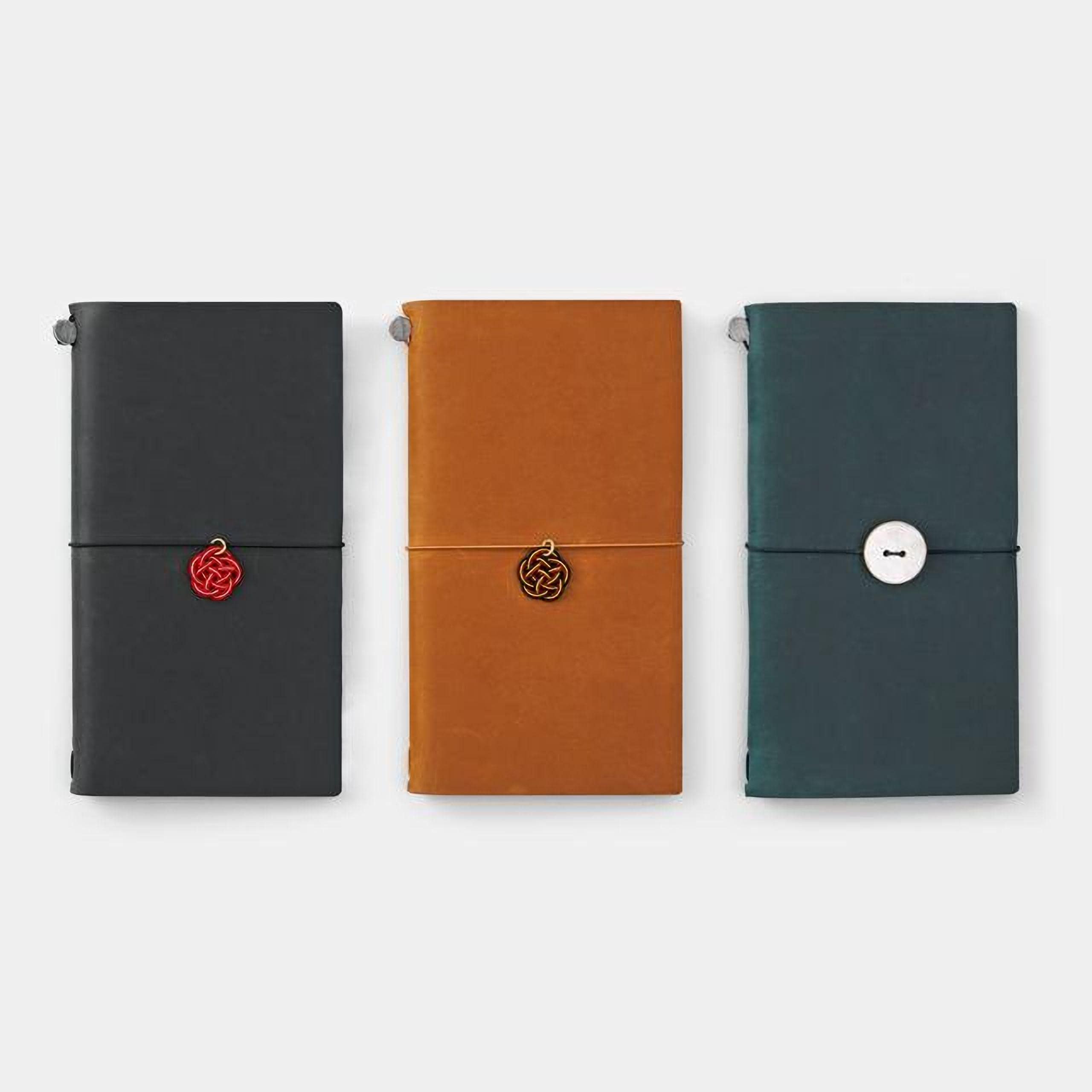 Three different colored notebooks or planners are arranged in a row, each with a unique design and color.
