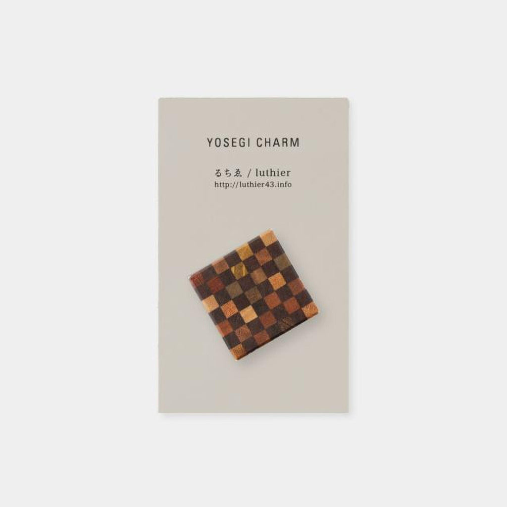a square-shaped charm with a checkerboard pattern on it.