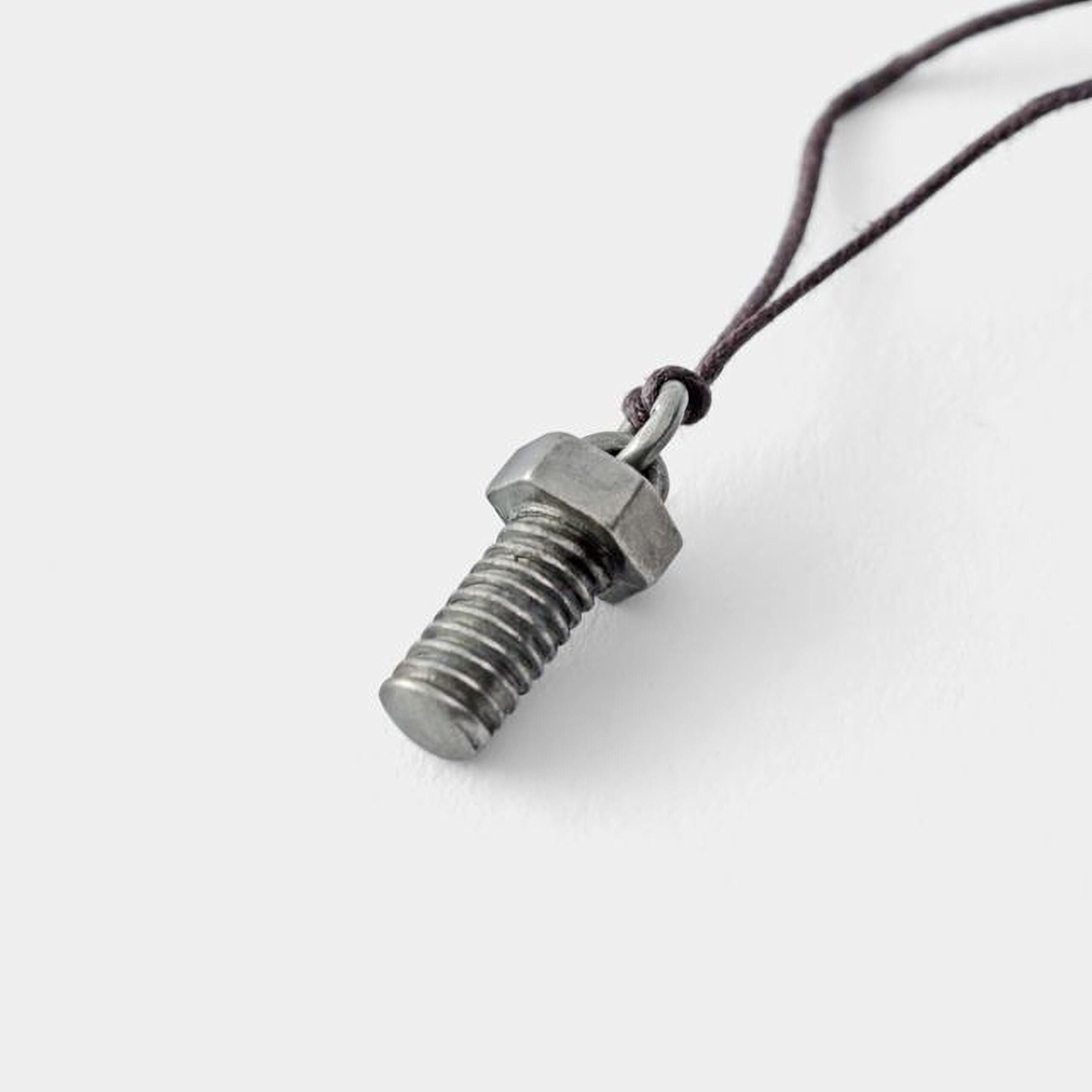 A silver-colored metal bolt or nut is hanging from a string.