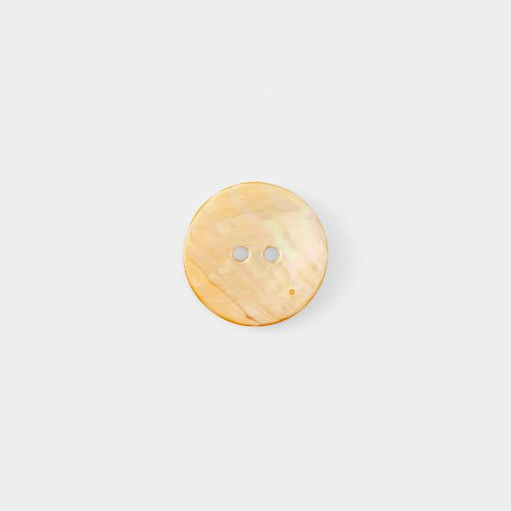A single, round, light-colored button is shown against a plain white background.