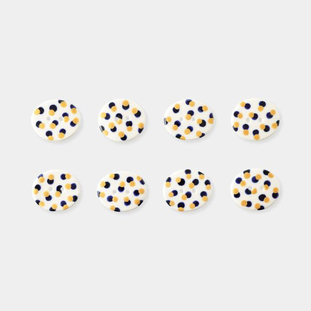 a collection of eight circular buttons with a polka dot pattern, arranged in two rows of four.