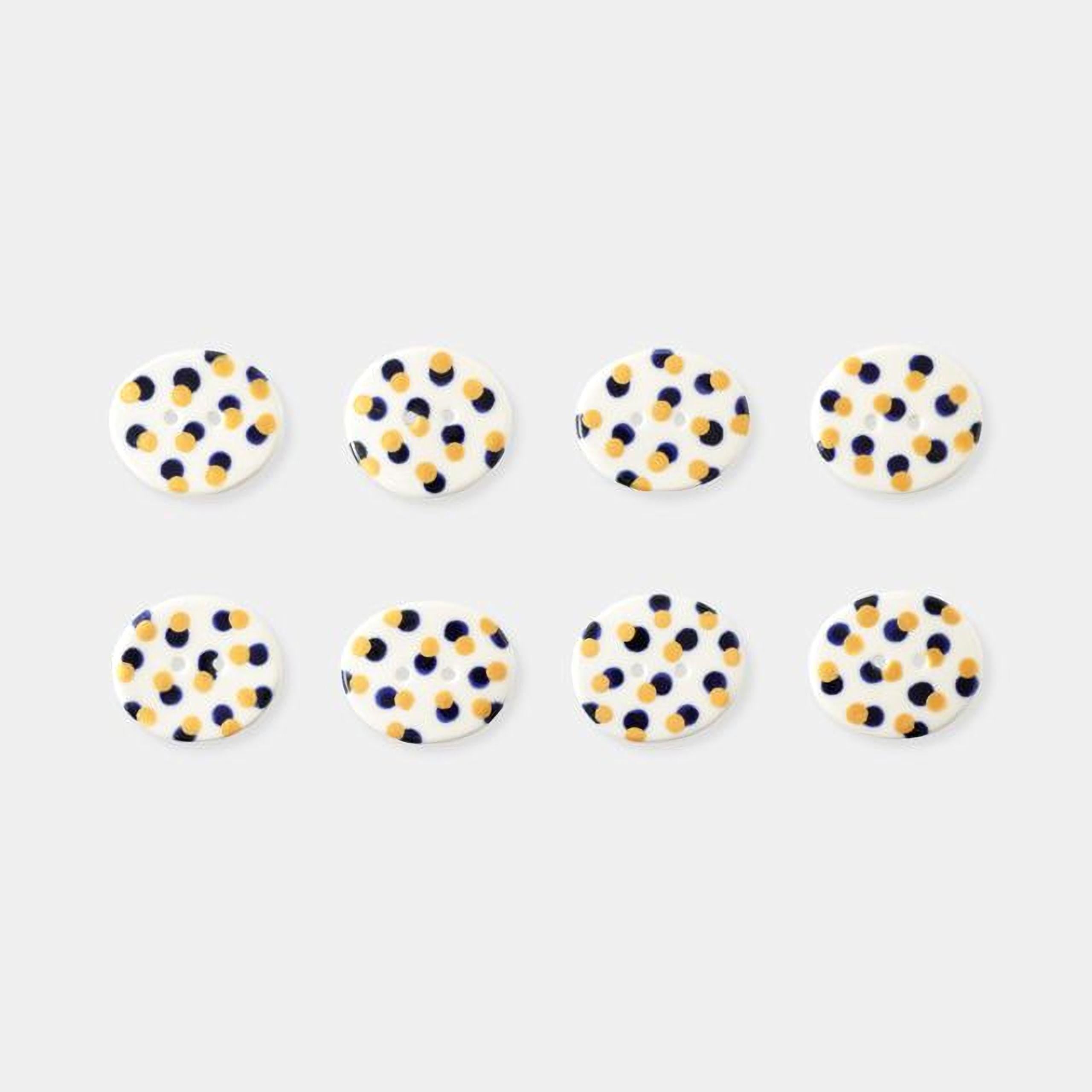 a collection of eight circular buttons with a polka dot pattern, arranged in two rows of four.