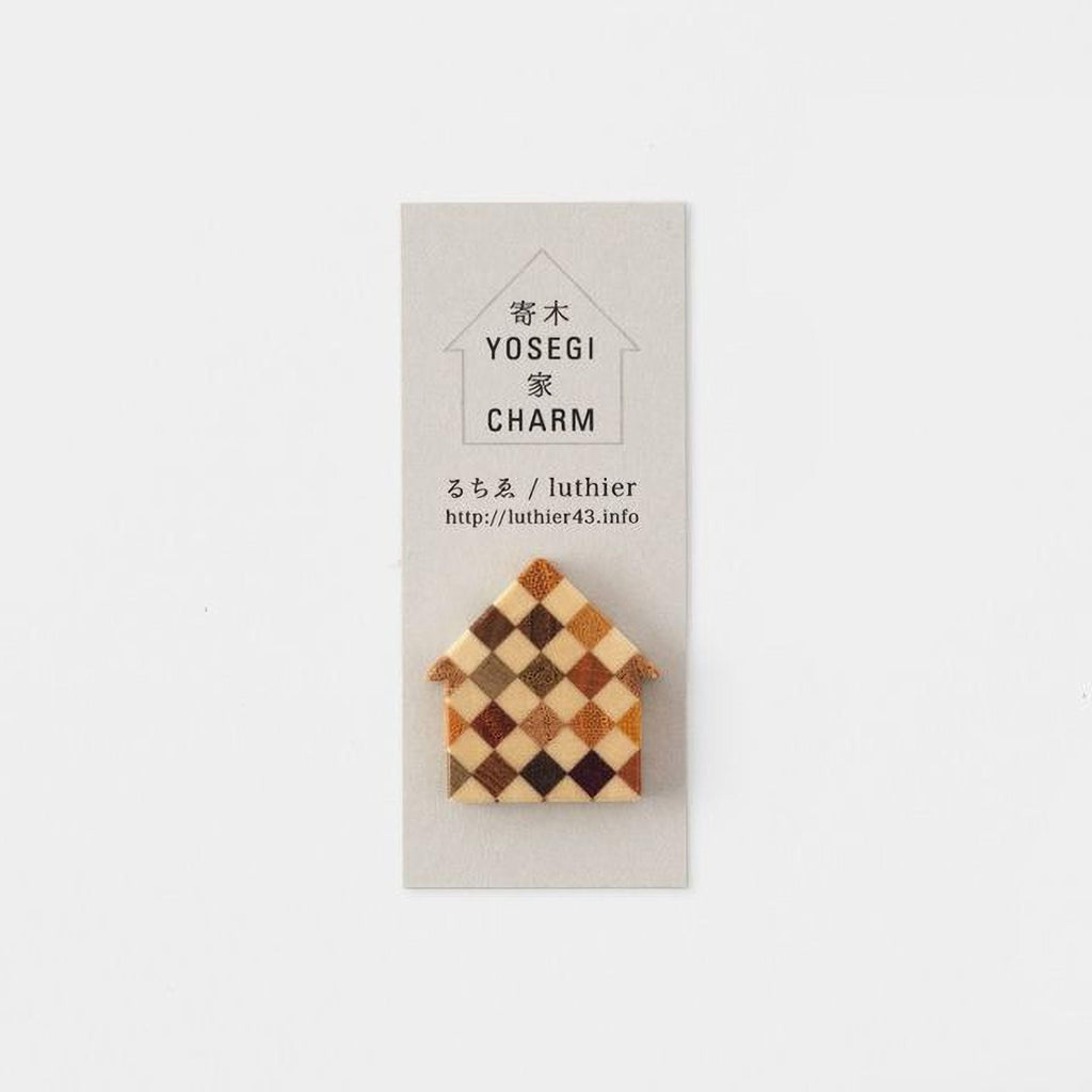 A small, wooden house-shaped pin is displayed against a light background.