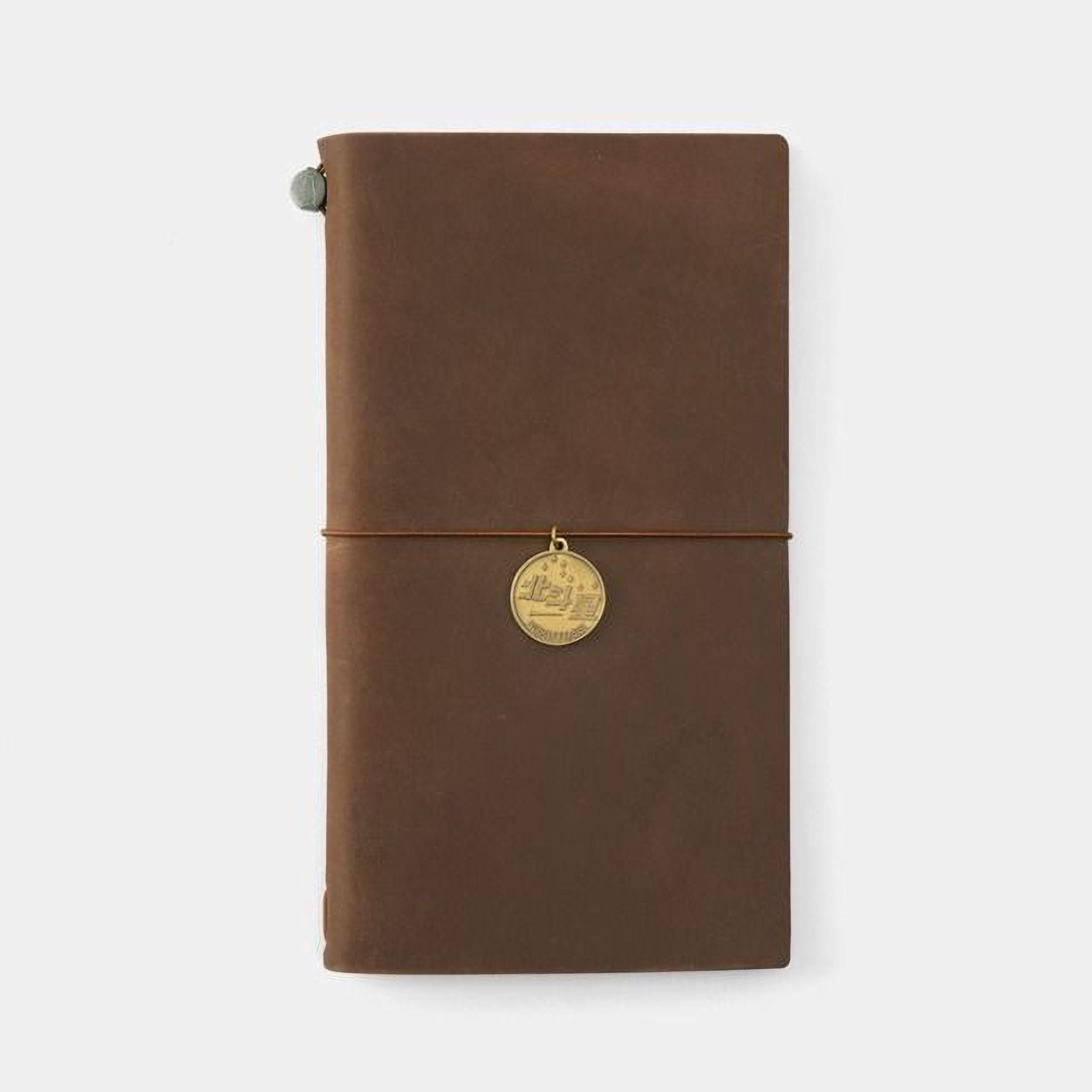 A brown leather-bound notebook with a gold-colored charm attached to the cover.