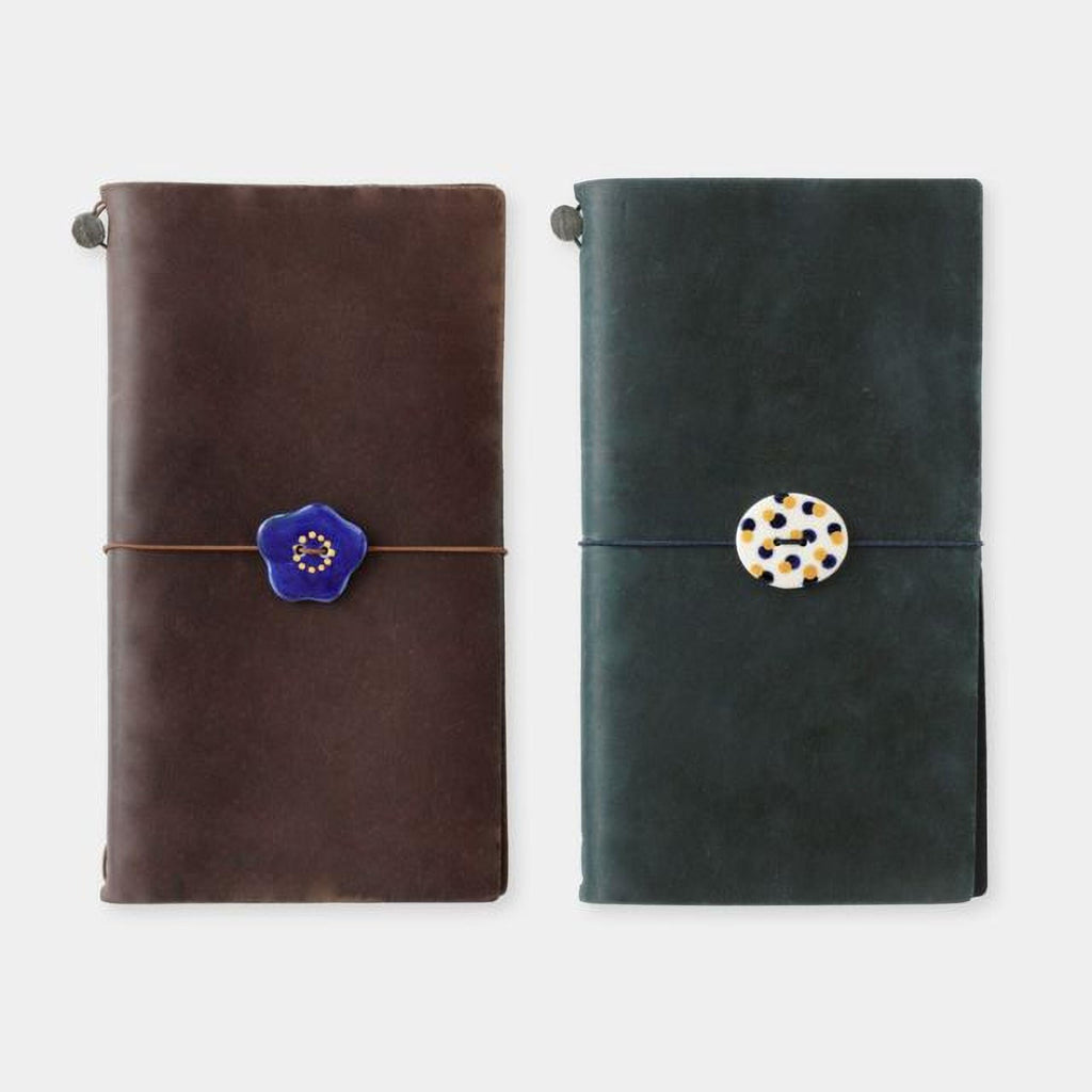 two leather-bound notebooks with decorative buttons on the covers.