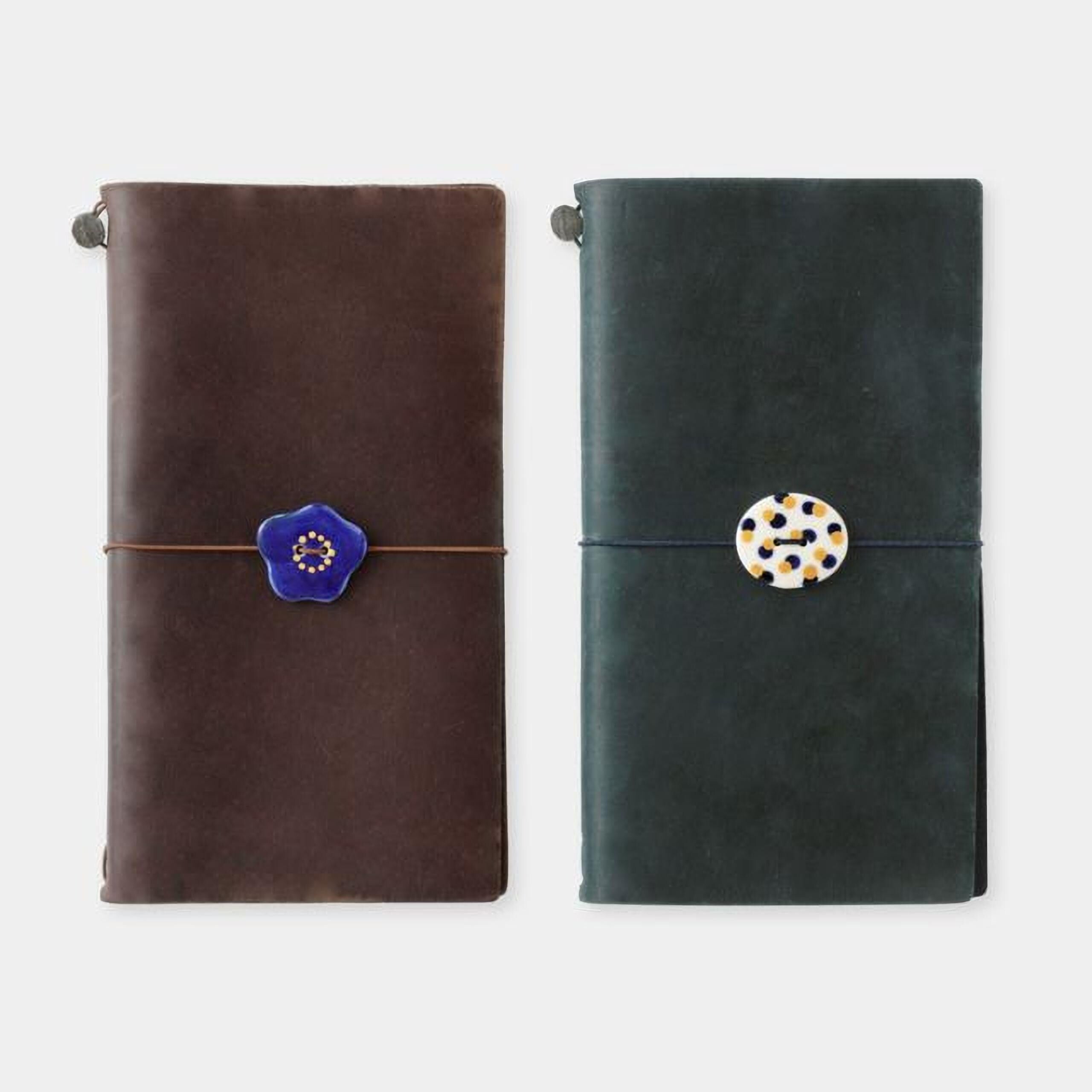 two leather-bound notebooks with decorative buttons on the covers.