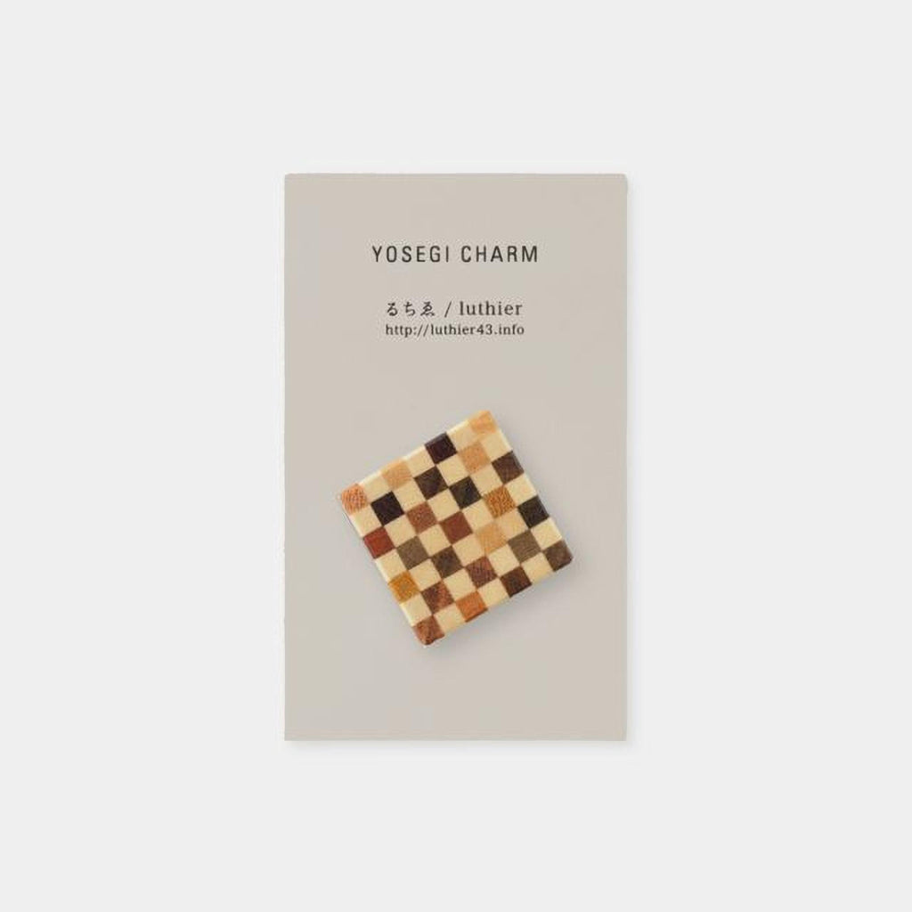 The image is a square-shaped charm with a checkerboard pattern on it, placed on a light-colored background.