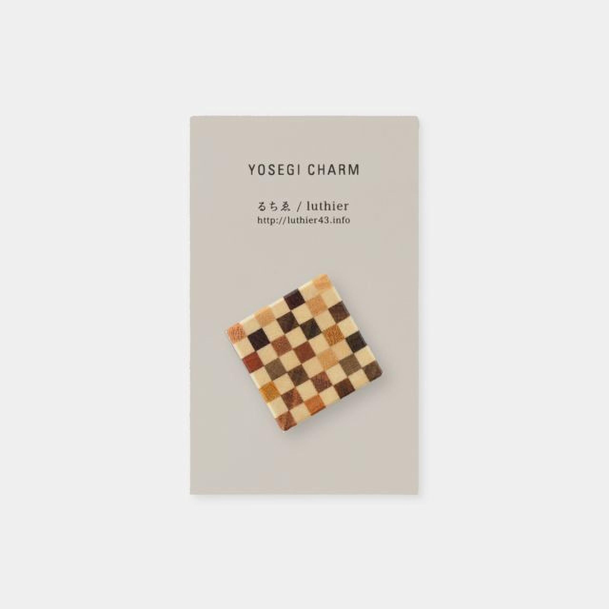 The image is a square-shaped charm with a checkerboard pattern on it, placed on a light-colored background.