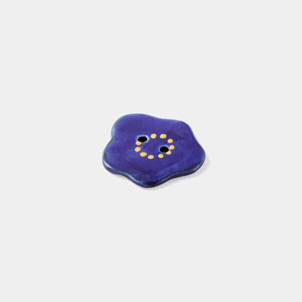 A single, blue button with a yellow dot pattern is shown against a plain white background.