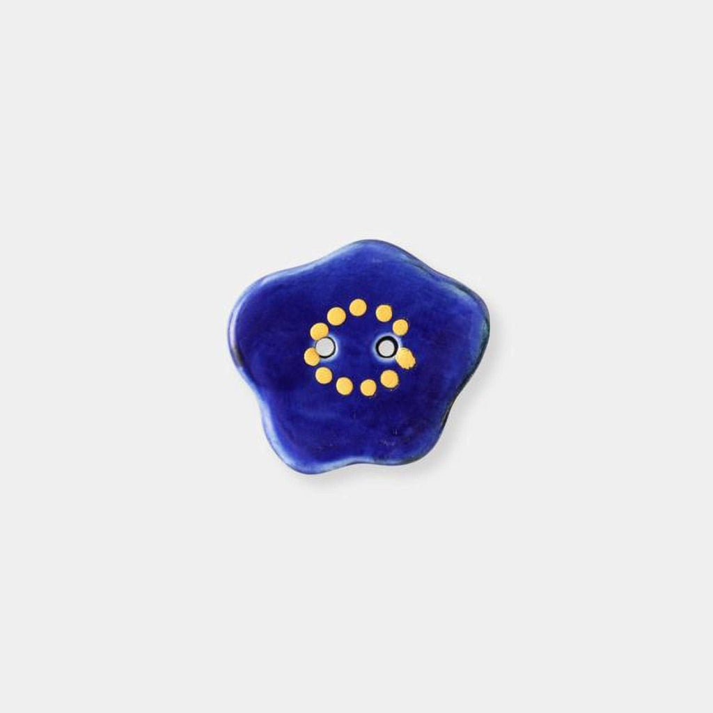 A blue flower-shaped object with yellow dots forming a smiley face.