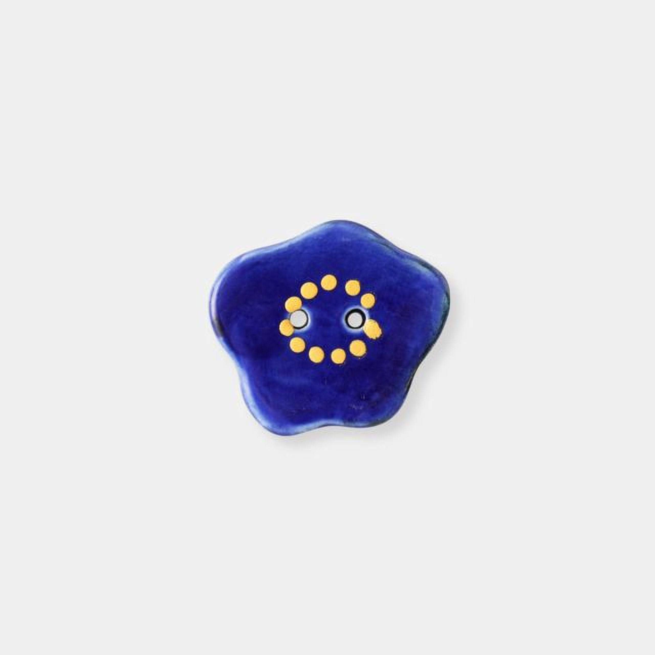 A blue flower-shaped object with yellow dots forming a smiley face.