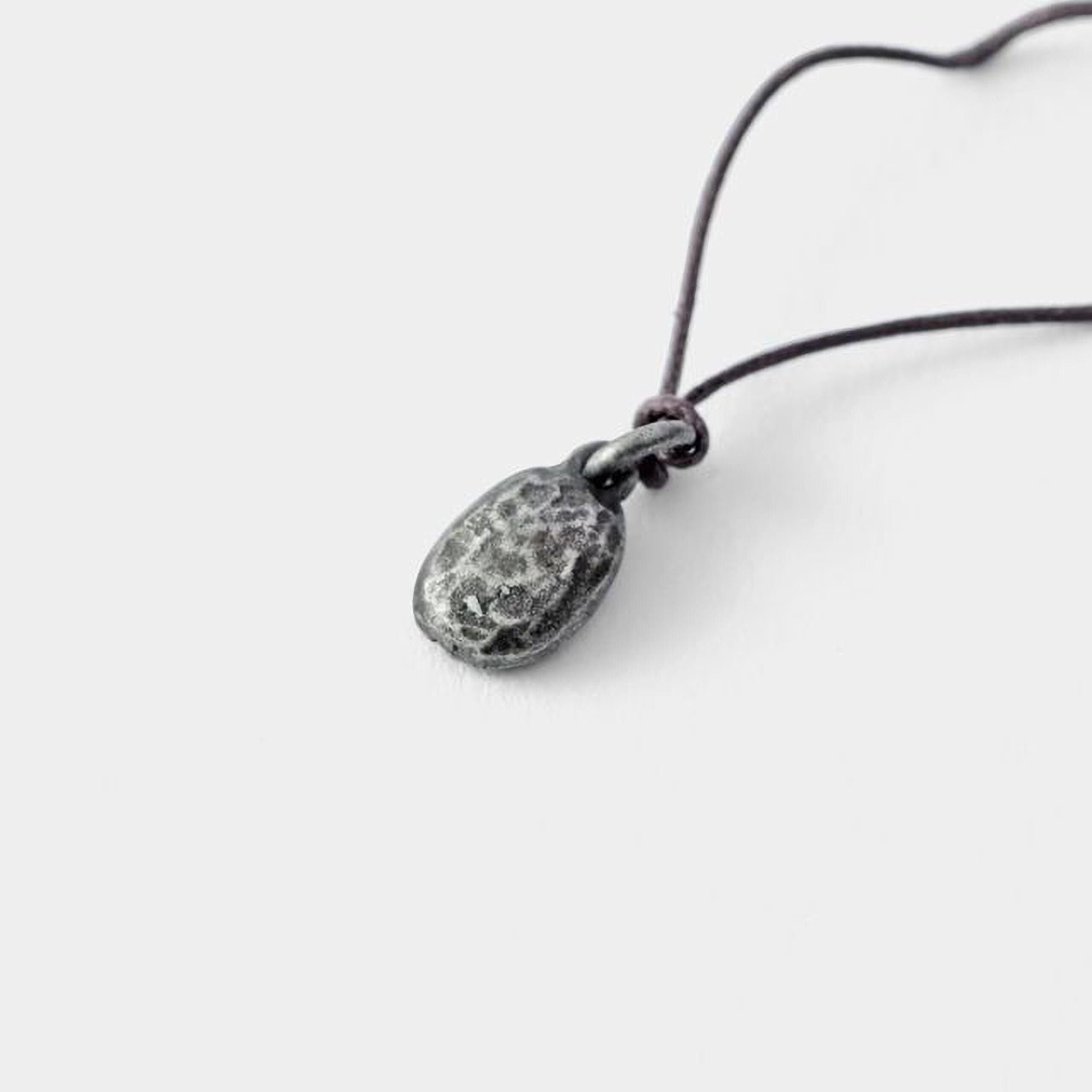 A silver pendant with a twisted cord is shown against a plain white background.