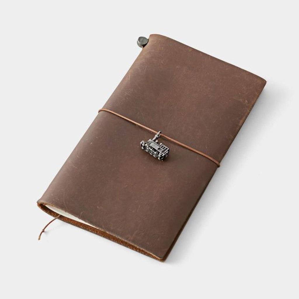 A brown leather-bound notebook with a metal charm attached to the cover.