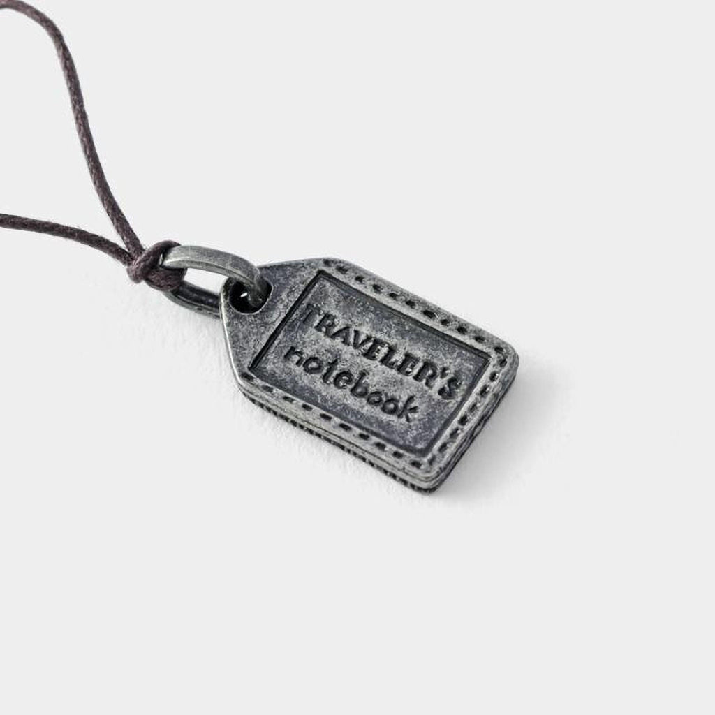 A small metal tag with the text "RAVELER'S notebook" engraved on it.