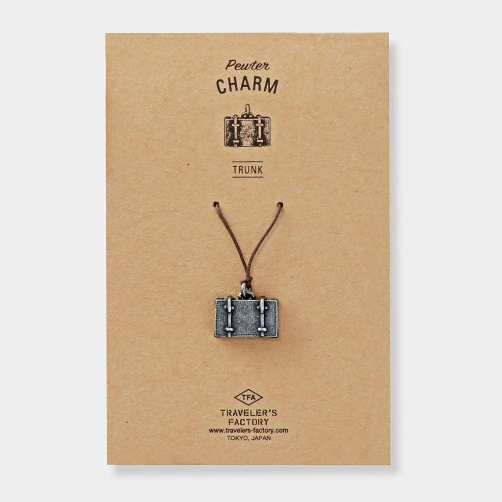 a small metal charm in the shape of a suitcase, hanging from a string.