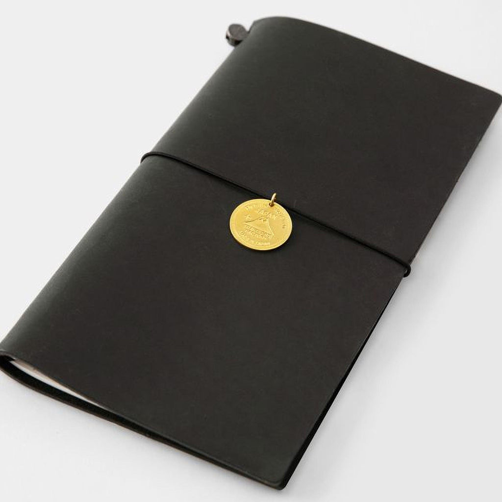 A black leather-bound notebook with a gold-colored charm attached to the cover.