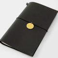 A black leather-bound notebook with a gold-colored charm attached to the cover.