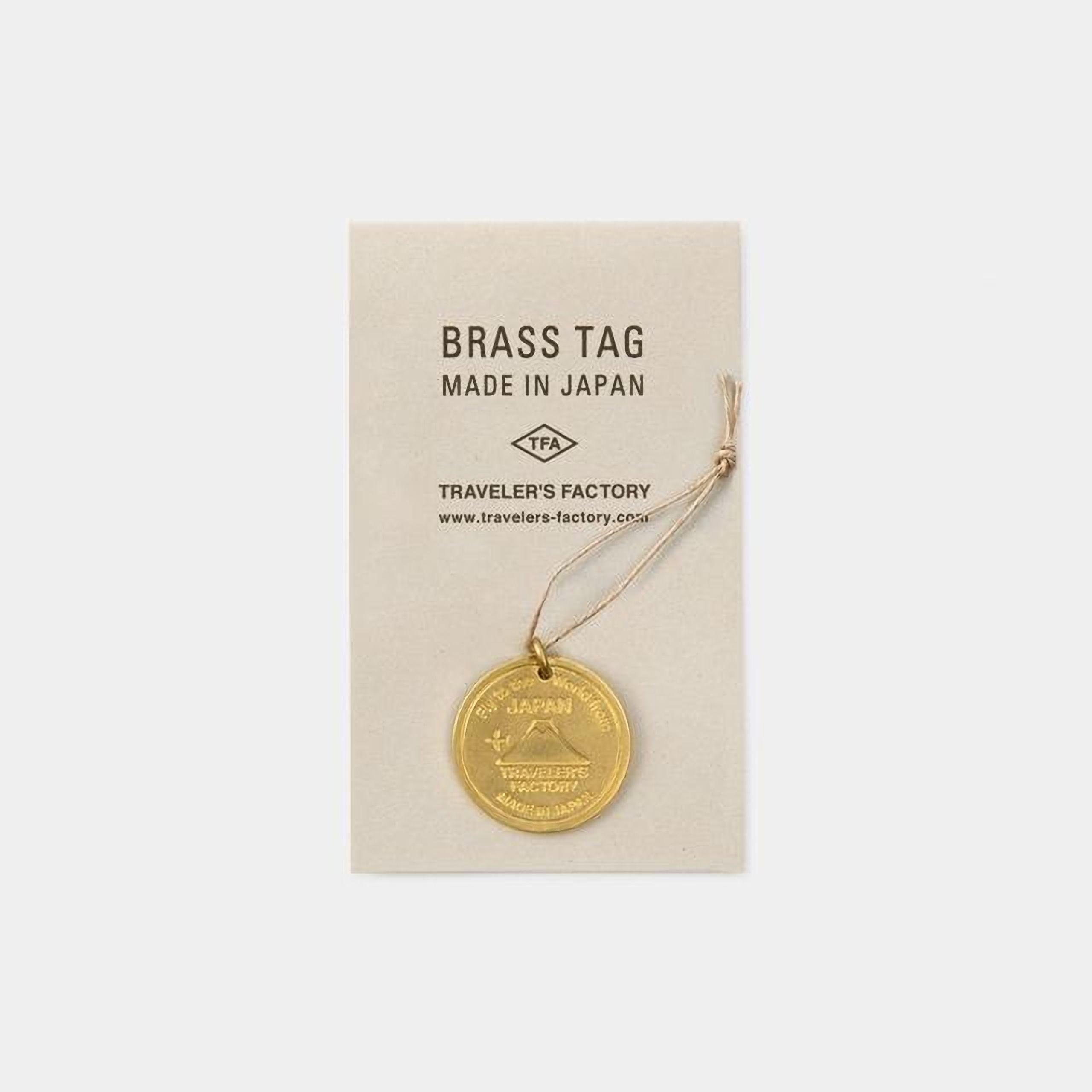 a brass tag with a gold-colored emblem, attached to a beige background.