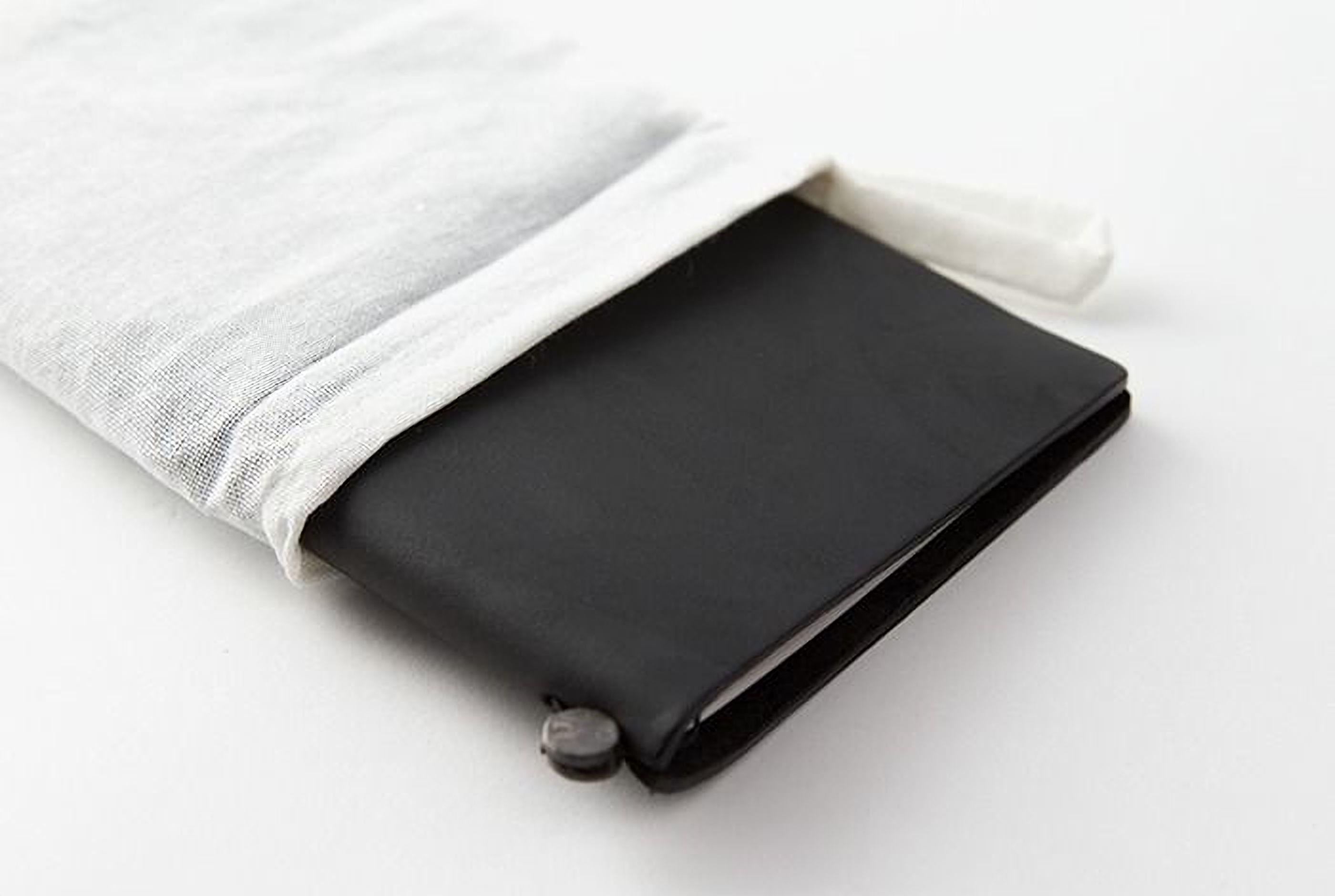 A black leather-bound notebook or journal is shown, with a white cloth bag partially covering it.