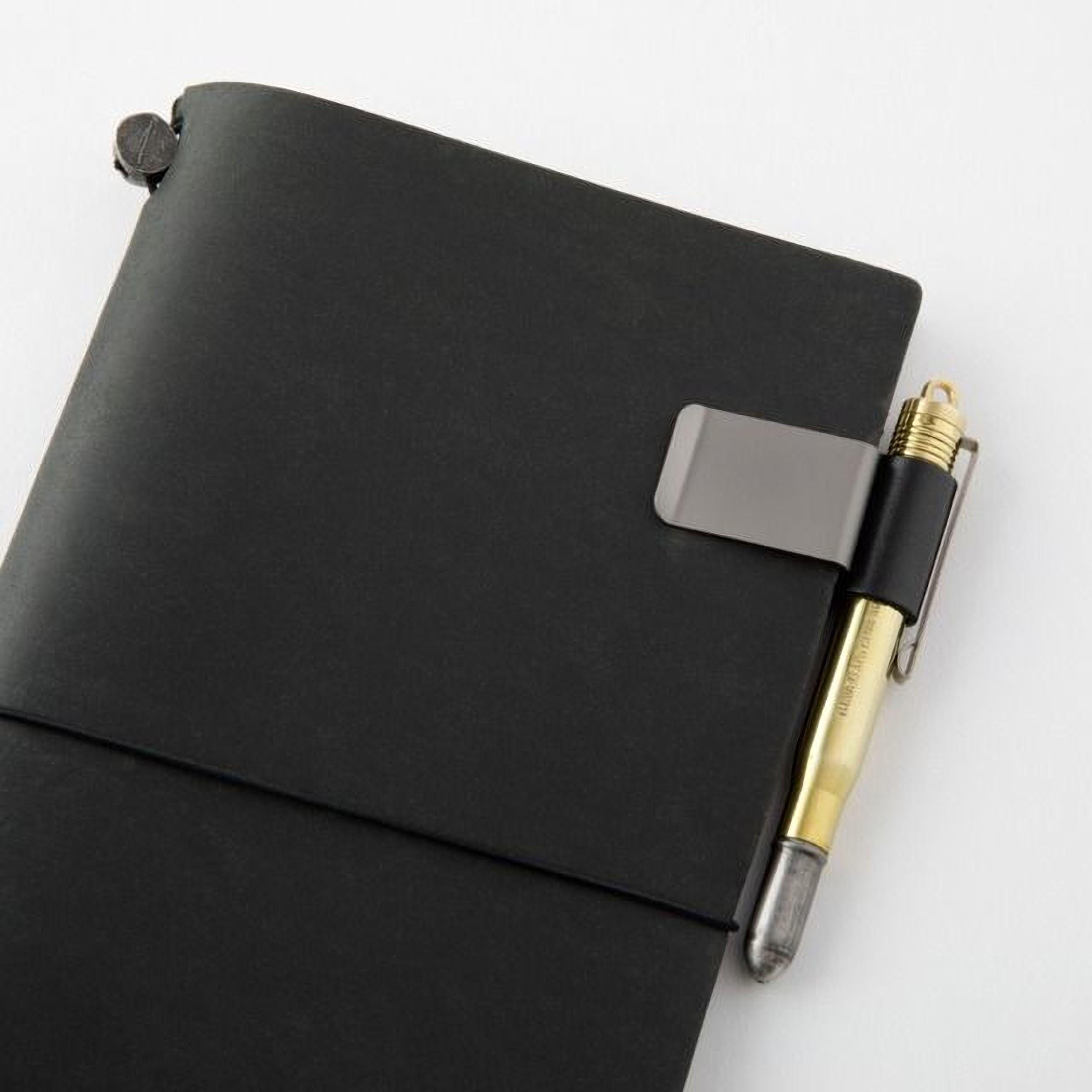 A black leather-bound notebook with a pen clip attached to it, resting on a white surface.