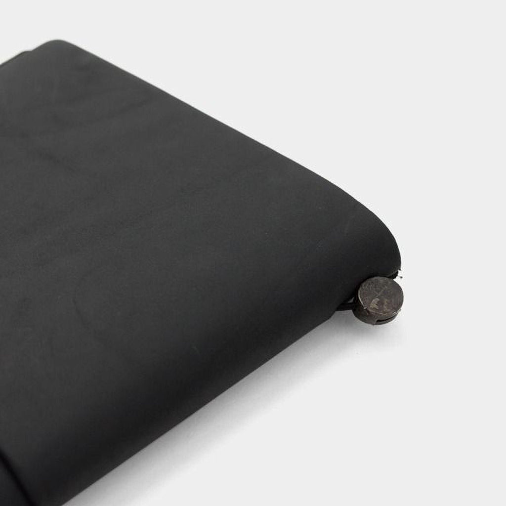 A black, rectangular object with a circular object attached to it, sitting on a white surface.