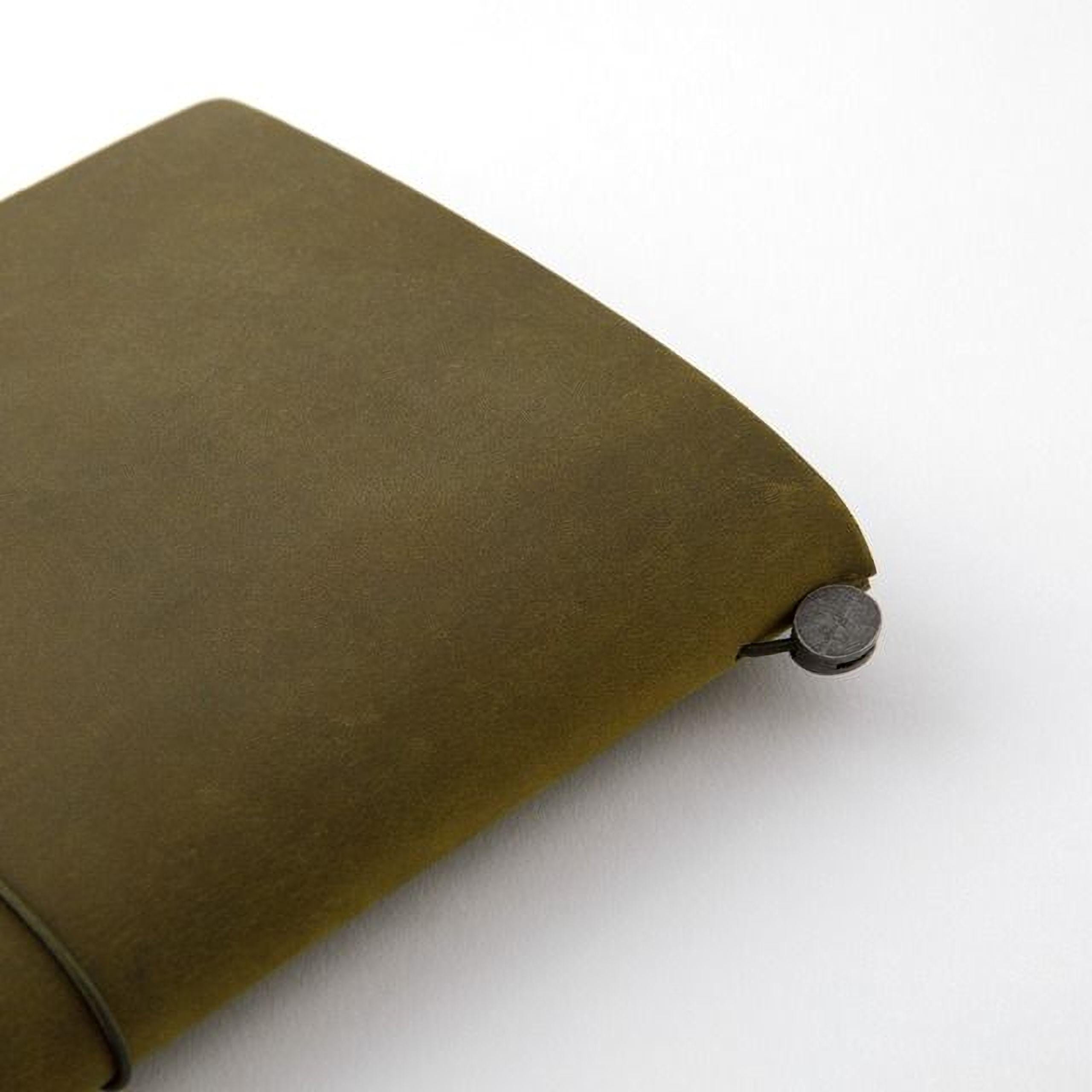 A close-up view of a dark green leather-like material, possibly a notebook or wallet, with a metal clasp or clasp-like attachment on the edge.